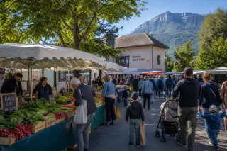 Outdoor market in Épagny Metz-Tessy with local vendors, fresh produce, villagers shopping, mountains and trees in the background